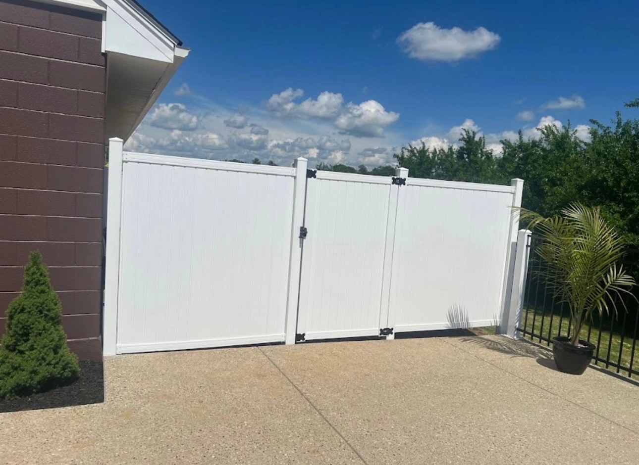 White double gate installed beside a brick home